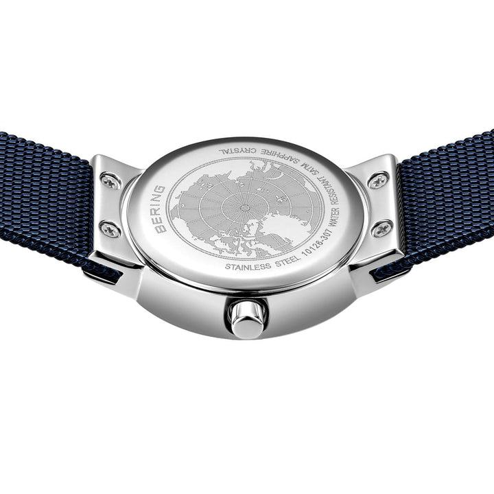 Een zilveren Bering horloge, model 10126-307, met een blauwe mesh band is vanaf de achterkant te zien, met een abstracte wereldkaart gravure samen met BERING en STAINLESS STEEL. Dit Quartz uurwerk benadrukt zijn kroon en bandbevestigingen.