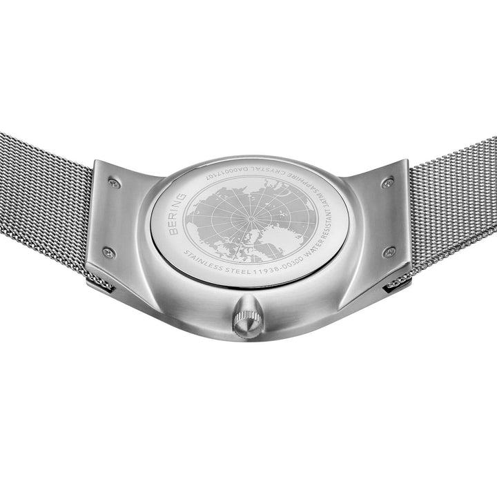 De afbeelding toont de achterkant van een Bering 11938-003DD, met een roestvrijstalen mesh-band, een gegraveerde kaart met tekst onder duurzaam saffierglas en een zilveren afwerking met een opwindkroon voor extra elegantie.