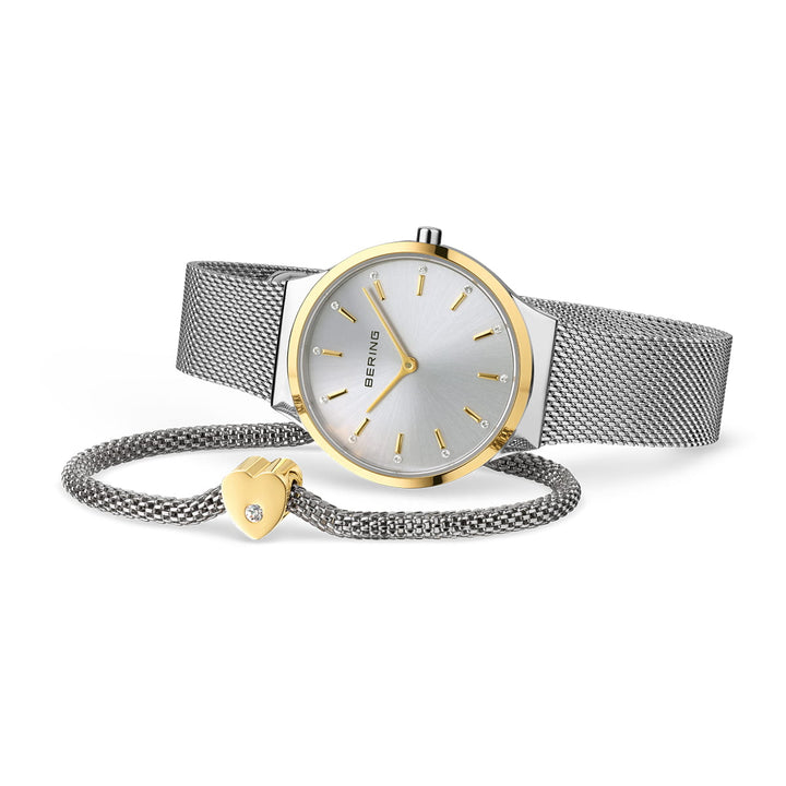Berings 12131-014-GWP heeft een zilveren polshorloge met een metalen mesh band, minimalistische zilveren wijzerplaat, quartz uurwerk en gouden uurmarkeringen en wijzers. Het wordt geleverd met een bijpassende zilveren armband versierd met een gouden hartbedel en saffierglas juweeldetails.