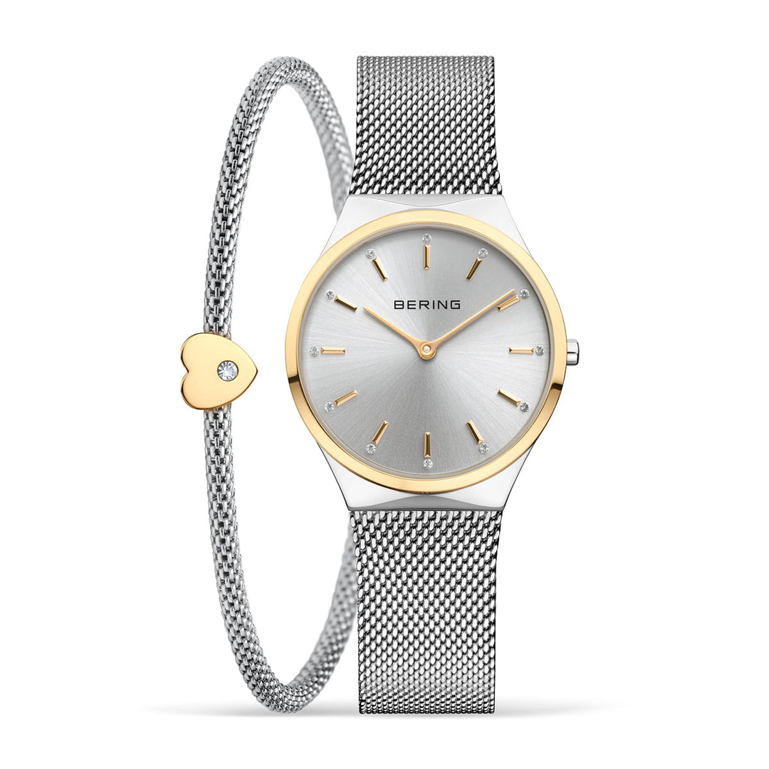 Het Bering horloge (12131-014-GWP) heeft een zilveren mesh band met gouden accenten, een bijpassende armband met een gouden hartbedel en diamant, een minimalistische zilveren wijzerplaat met een quartz uurwerk beschermd door saffierglas en elegante gouden uurmarkeringen.