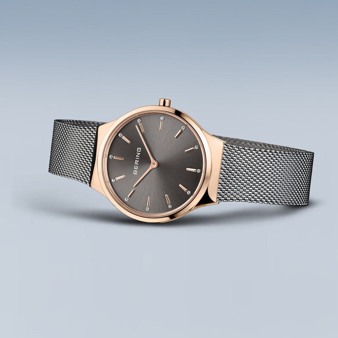Het Bering polshorloge, model 12131-339-GWP, heeft een roségouden kast en Milanese band. De donkergrijze wijzerplaat heeft minimalistische markeringen en wijzers, aangestuurd door Quartz-uurwerk voor precisie.
