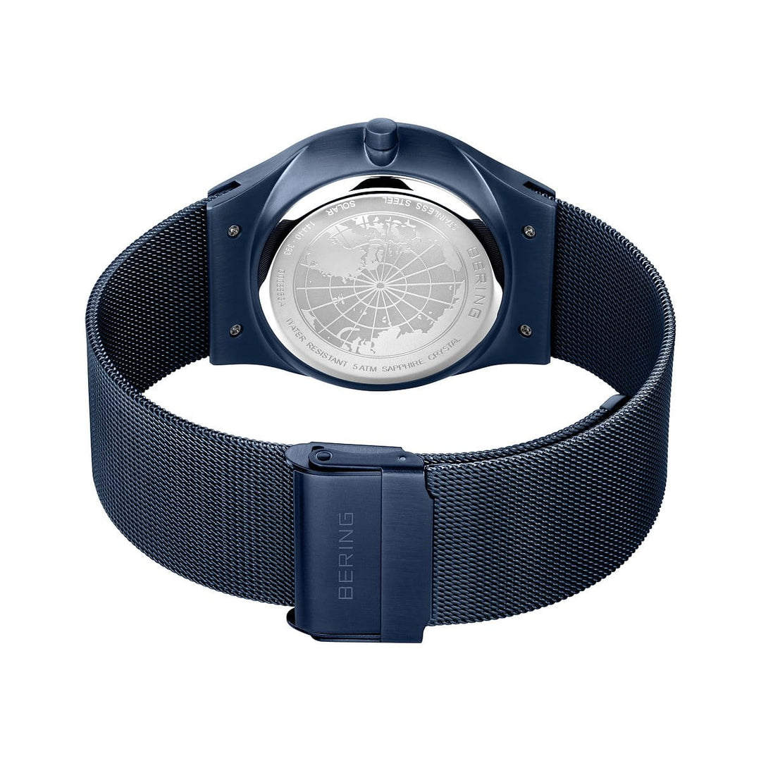 Het Bering 14440-393 herenhorloge heeft een marineblauwe meshband met een reliëfopdruk van BERING op de sluiting, een achterkant met een gegraveerde wereldkaart en tekst in een ronde gepolijste afwerking, aangevuld met duurzame saffierglas bescherming.