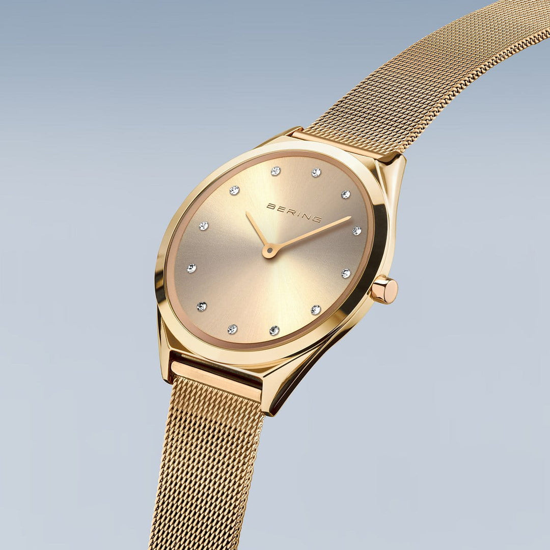 Het Bering 17031-333 dameshorloge heeft een gouden design met een strakke mesh band, minimalistische wijzerplaat en kristallen uurmarkeringen. Het heeft een saffierglas wijzerplaat met een zachte gradiënt glans, aangestuurd door quartz uurwerk en bevat een enkele kroon aan de rechterkant.