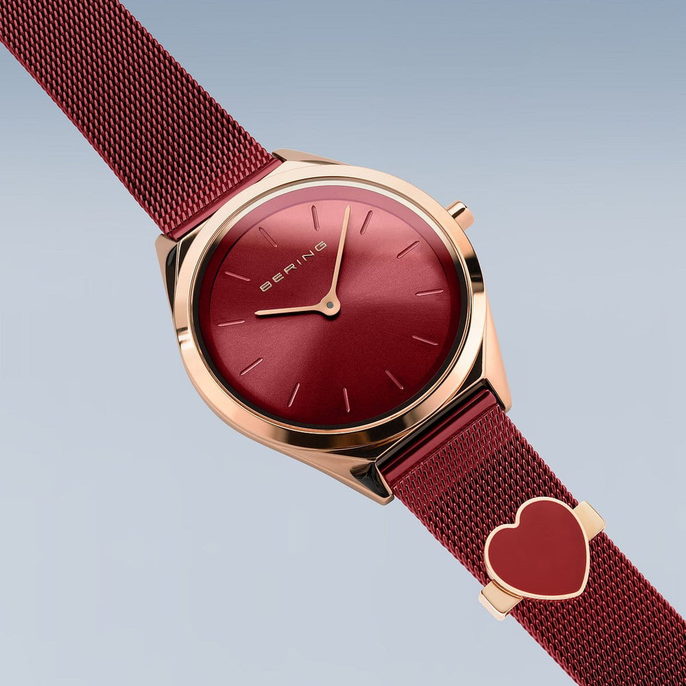 Ontdek de elegantie van Berings 17031-363-GWP dameshorloge, met een strak design met een rode Milanese band en wijzerplaat, gehuisvest in een gouden kast. Minimalistische uurmarkeringen worden versterkt door hartvormige details op de band tegen een gradiëntachtergrond.