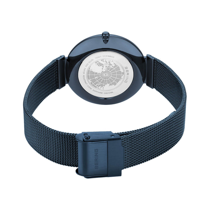 De afbeelding toont een Bering dameshorloge met een elegante Milanees band en gesloten sluiting. De kastachterkant gravering van een wereldbol met inscripties benadrukt het strakke design van de bering dameshorloge blauwe dial - 18132-399.