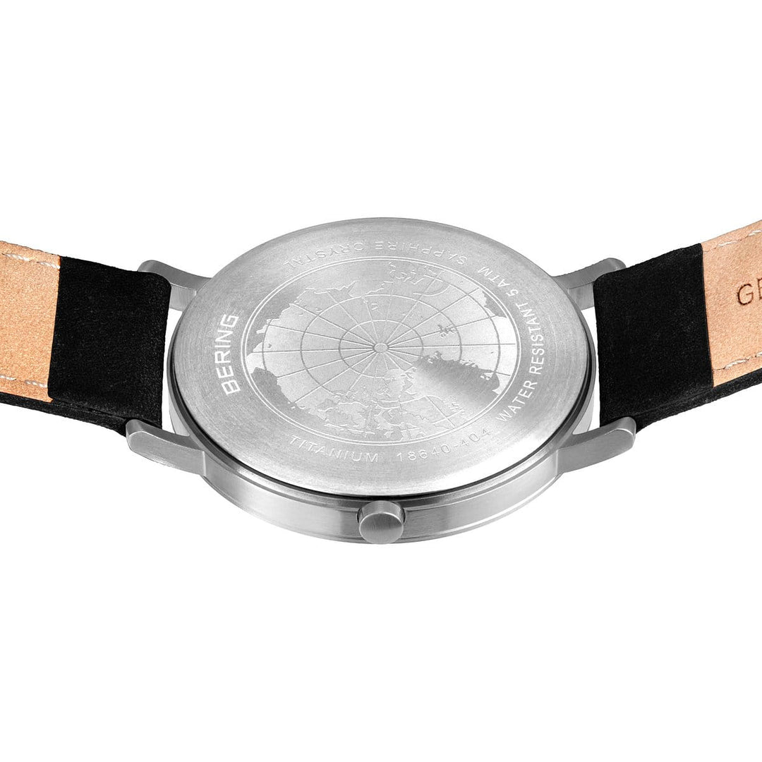 De afbeelding toont de achterkant van een Bering heren horloge witte dial - 18640-404, met een gegraveerd kaartontwerp. De elegante titanium horlogekast en lugs worden aangevuld met gedeeltelijk zichtbare banden met lichtbruin leer en zwarte stof, die perfect passen bij het quartz-uurwerk.
