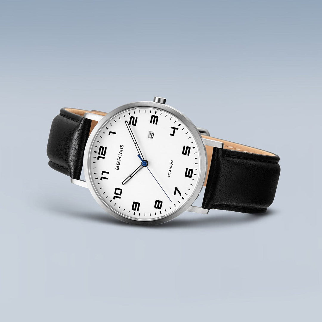Het Bering heren horloge 18640-404 heeft een minimalistisch design met een witte wijzerplaat, zwarte Arabische cijfers en een datumvenster op 3 uur. Het heeft een zilveren titanium kast en een zwarte leren band, aangestuurd door een precisie Quartz uurwerk.