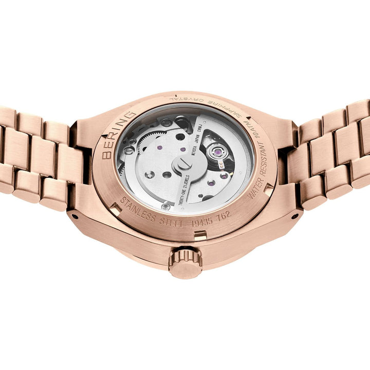 Het bering dameshorloge 19435-762 van Bering heeft een roségouden ontwerp met een open achterkant waarop het mechanische uurwerk zichtbaar is, een roestvrijstalen kast en band en gravures zoals BERING.