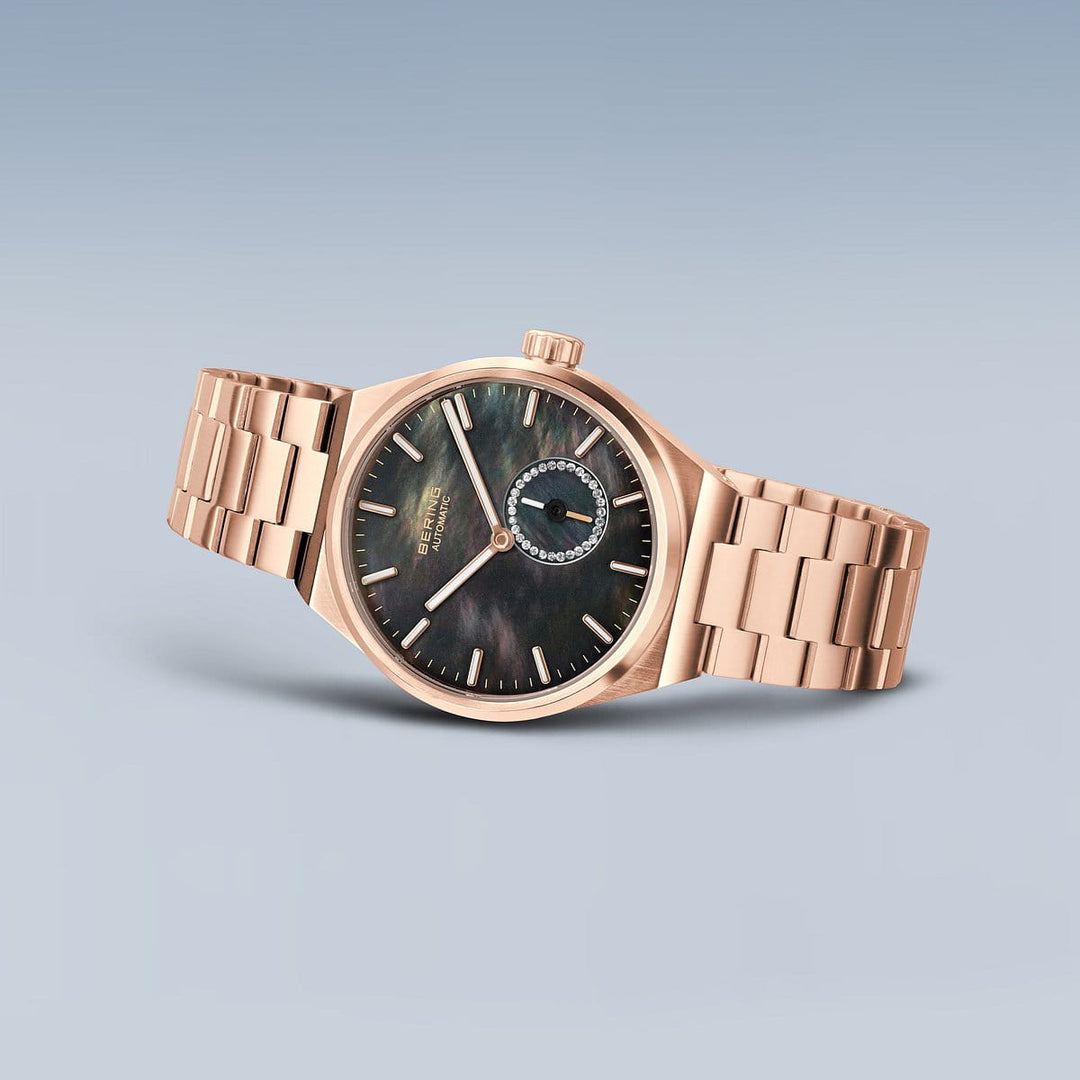 Het Bering dameshorloge (19435-762) heeft een roségouden ontwerp met een zwarte wijzerplaat, met gouden uurmarkeringen en wijzers. Het omvat een kleine subdial op 8 uur met een bejeweled rand, alles gevat in een roestvrijstalen kast en aangevuld met een bijpassende metalen schakelband.