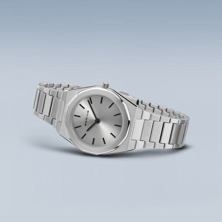 Het Bering dames horloge zilveren dial - 19632-700 heeft een strak zilveren design met een metalen band, minimalistische ronde wijzerplaat, eenvoudige zwarte wijzers en een kleine kroon. Het heeft een nauwkeurig quartz uurwerk en een zachte gradiënt lichtblauwgrijze achtergrond.