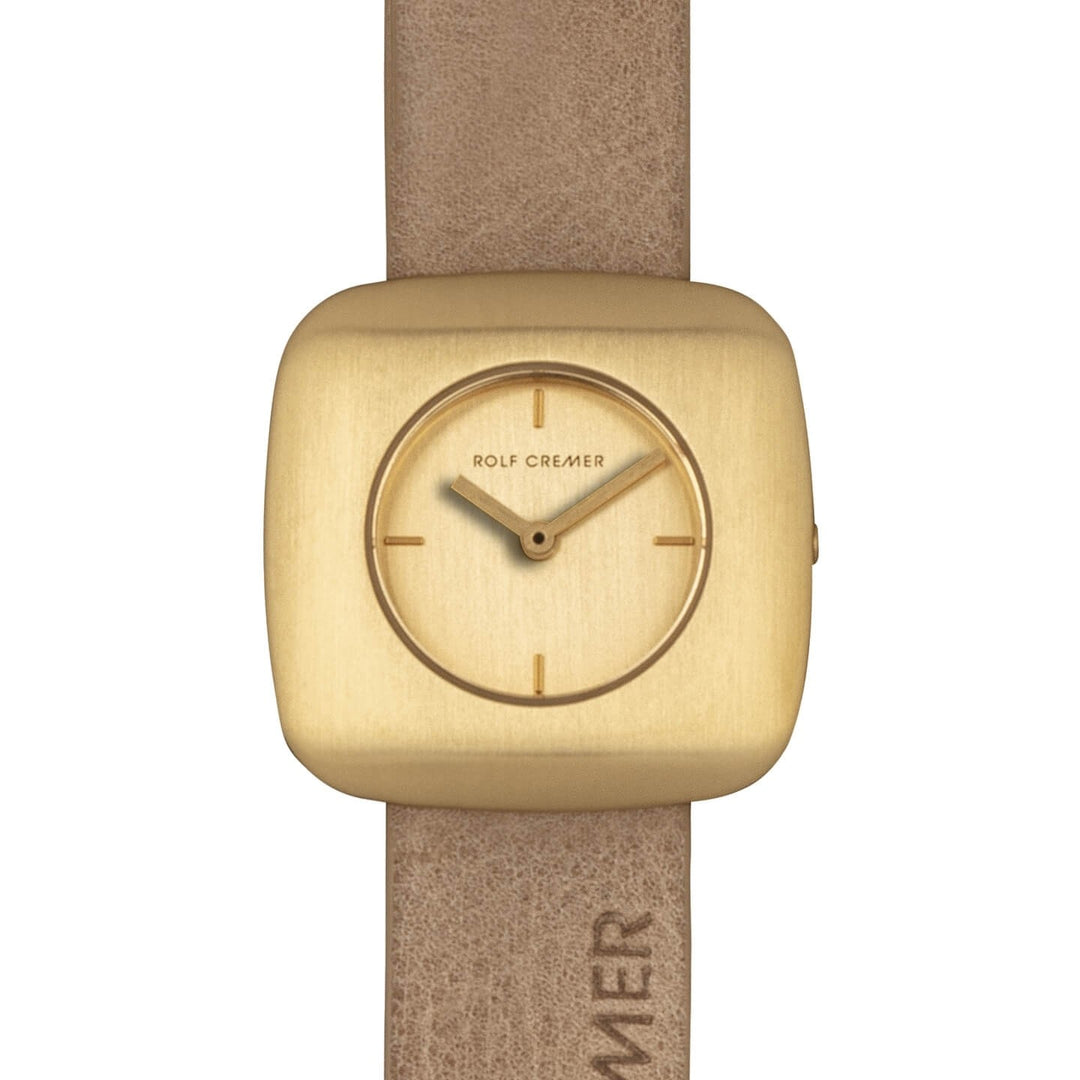 Het Rolf Cremer Horloge 508011 Edge is een elegant dameshorloge met een vierkante goudkleurige wijzerplaat, minimale uurmarkeringen en kleine wijzers. Het beschikt over een quartz uurwerk en een bruine leren band, met Rolf Cremer op zowel de wijzerplaat als de reliëfband.