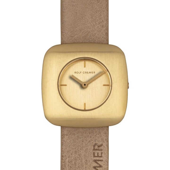 Het Rolf Cremer Horloge 508011 Edge is een elegant dameshorloge met een vierkante goudkleurige wijzerplaat, minimale uurmarkeringen en kleine wijzers. Het beschikt over een quartz uurwerk en een bruine leren band, met Rolf Cremer op zowel de wijzerplaat als de reliëfband.