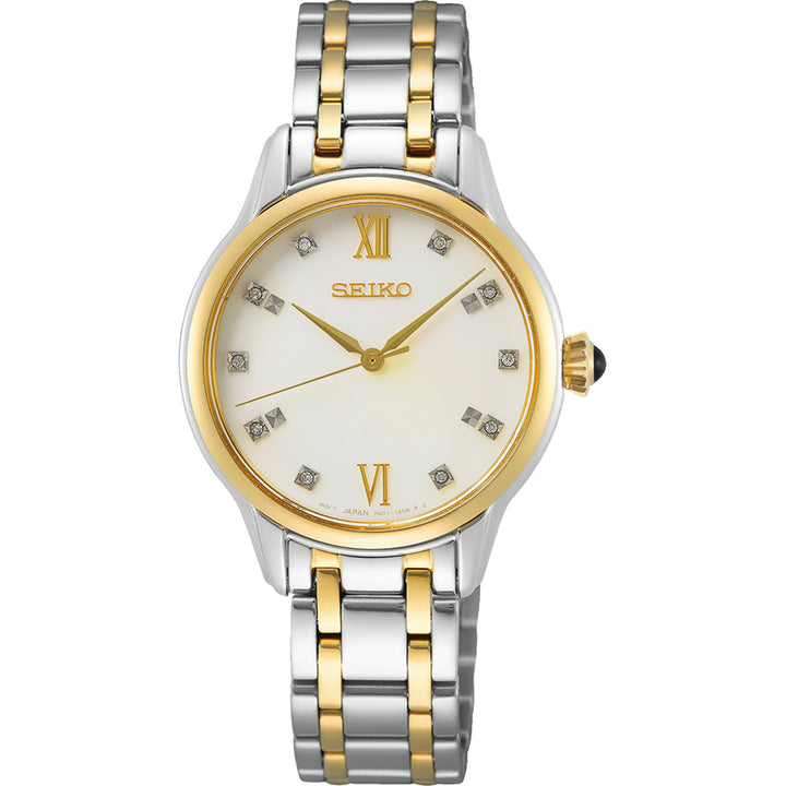 Het Seiko dameshorloge SRZ544P1 heeft een tweekleurige zilveren en gouden metalen band, een ronde witte wijzerplaat met diamanten uurmarkeringen, gouden Romeinse cijfers op 12 en 6 en strakke gouden wijzers. Het is gehuisvest in een roestvrijstalen kast met nauwkeurig quartz uurwerk voor een elegante touch.