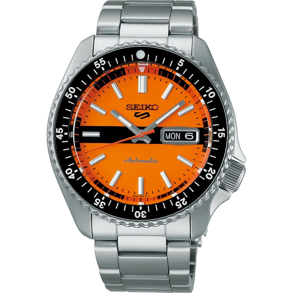 De Seiko 5 Sports SRPK11K1 heeft een zilveren roestvrijstalen band en een oranje wijzerplaat met witte markeringen en wijzers. De zwarte lunette heeft minutenmarkeringen en toont de dag/datum aan de rechterkant. Dit automatische horloge is waterbestendig tot 10ATM.