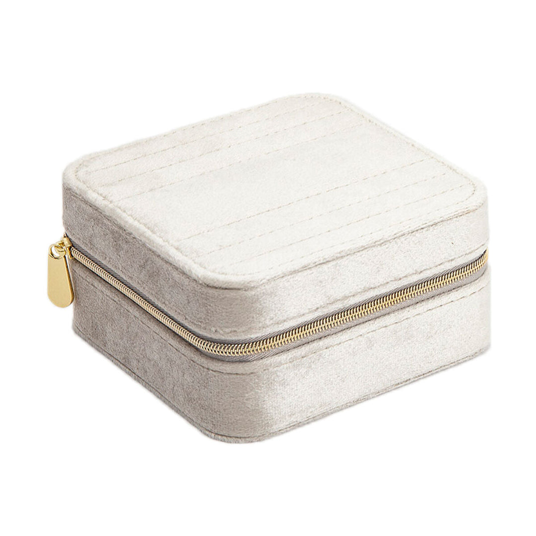 De Van der Kooij Collectie sieradendoos crème toebehoren is een klein, vierkant, lichtbeige sieradendoosje met een gouden rits en afgeronde hoeken, perfect voor dames, afgebeeld op een witte achtergrond.