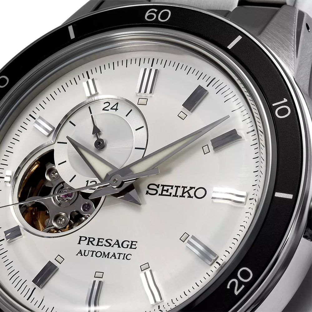 Close-up van het Seiko Presage heren horloge SSA423J1, met een zilverkleurige en witte wijzerplaat, roestvrijstalen kast, 24-uurs subdial, open-heart design met automatisch uurwerk, metalen uurmarkeringen en een genummerde lunette.