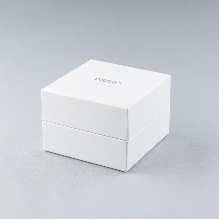 De witte vierkante doos met Seiko in grijs gedrukt suggereert een minimalistisch ontwerp tegen een zachte grijze achtergrond. Binnenin bevindt zich de verfijnde Seiko Presage heren horloge SSA405J1, bewonderd om zijn automatische uurwerk, perfect voor de veeleisende herenhorlogeliefhebber.