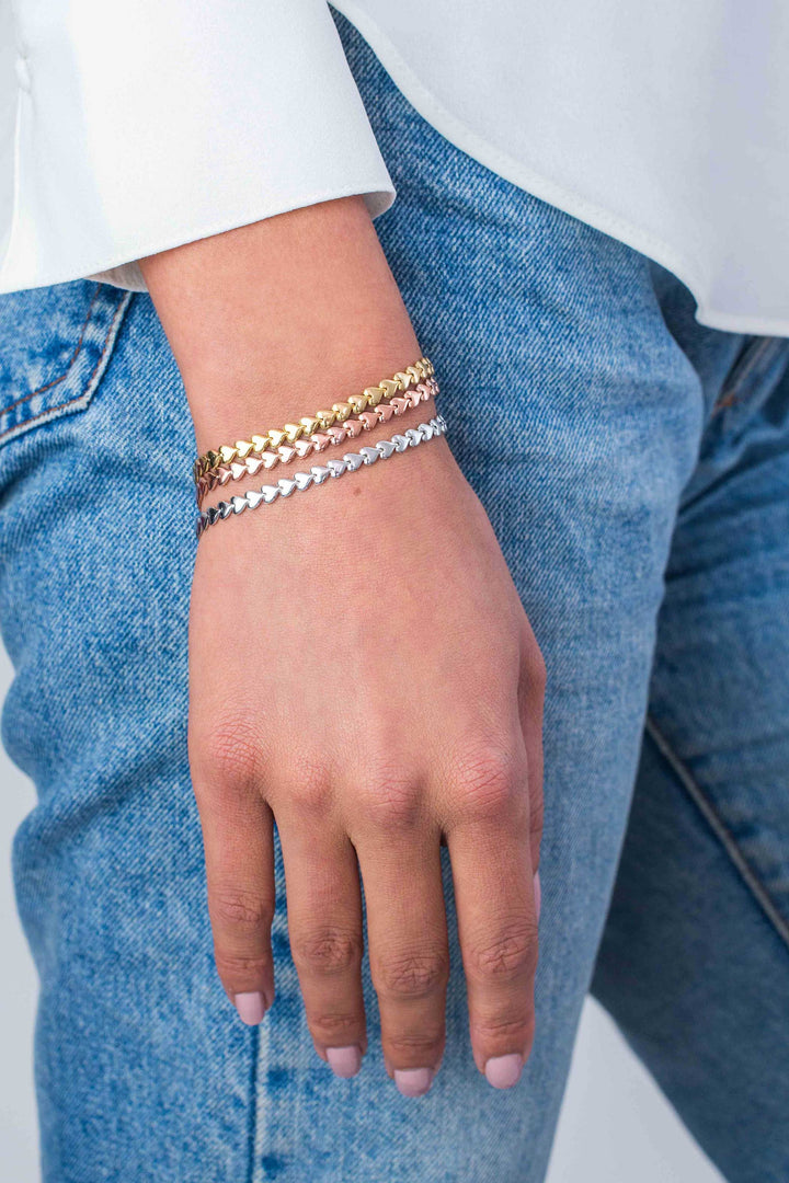 Een close-up van een hand die de Zinzi Armband Zilver Zia1798 draagt, rust op blauw denim. Een wit shirt met lange mouwen accentueert de delicate charme van deze elegante zilveren armband van Zinzi.