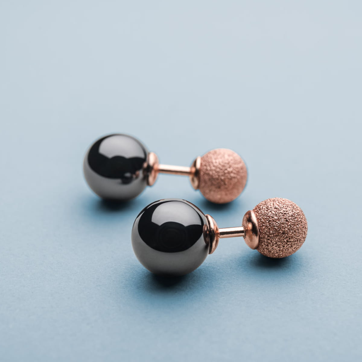 Ohrringe mit schwarzen Kugeln und roségoldenem, strukturiertem Detail