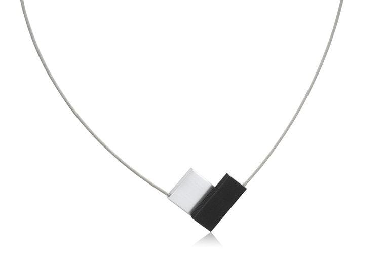 Collier in V-vorm mit schwarzem und weißem Anhänger an einem dünnen Draht.
