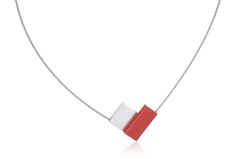 Collier mit V-förmigem roten und weißen Anhänger an einem silbernen Draht.
