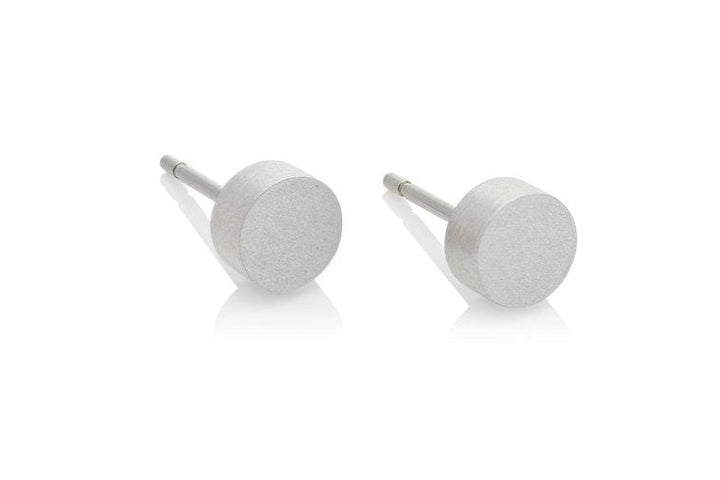De Oorsteker Klein rond O36 oorbellen van CLIC Creations zijn zilverkleurige, cilindrische oorstekers met platte ronde voorkanten, afgebeeld op een witte achtergrond. Handgemaakt in Nederland, ze hebben rechte stekers en een subtiele reflectie die bijdraagt aan hun strakke, minimalistische ontwerp. Ook hypoallergeen.