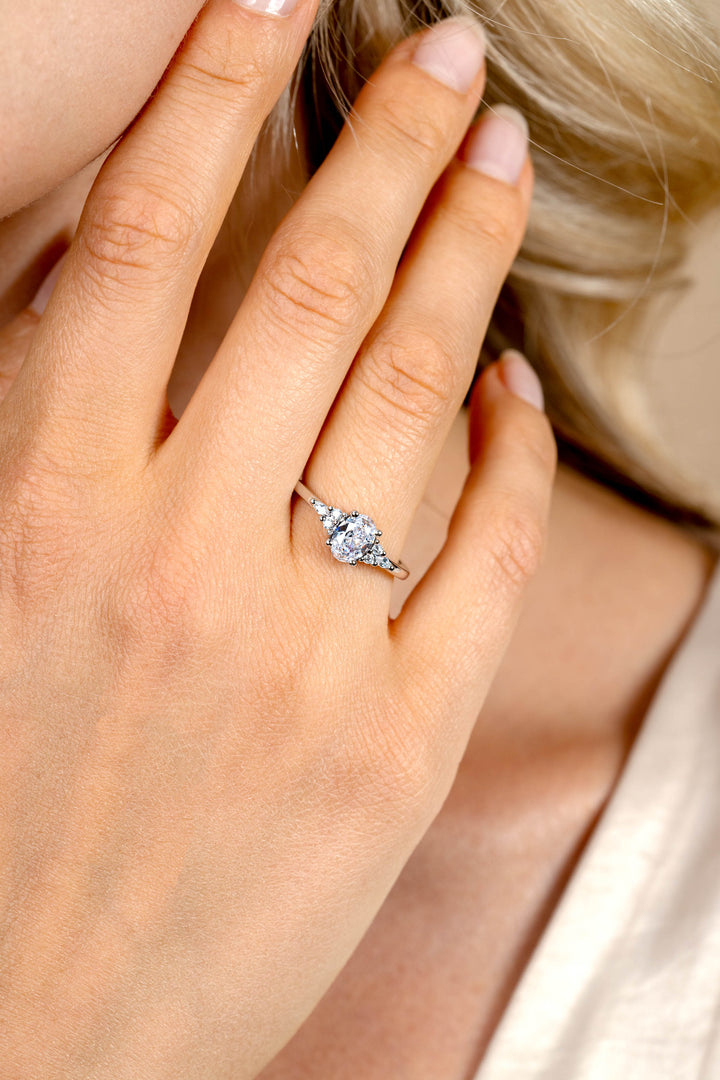 Een close-up van een vrouwenhand met gemanicuurde nagels, met de sprankelende Zinzi Ring zilver ZIR2698 van Zinzi aan haar ringvinger. De zacht wazige achtergrond accentueert de schittering van deze prachtige zilveren ring.