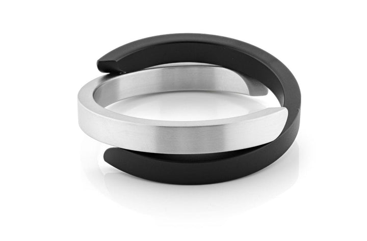 De Armband Cs gekruist Zwart A1Z van CLIC Creations is een modern, handgemaakt ontwerp uit Nederland met met elkaar verweven gepolijste metalen en matzwarte segmenten met gladde lichtreflecterende oppervlakken en een functionele magnetische sluiting voor gemak.