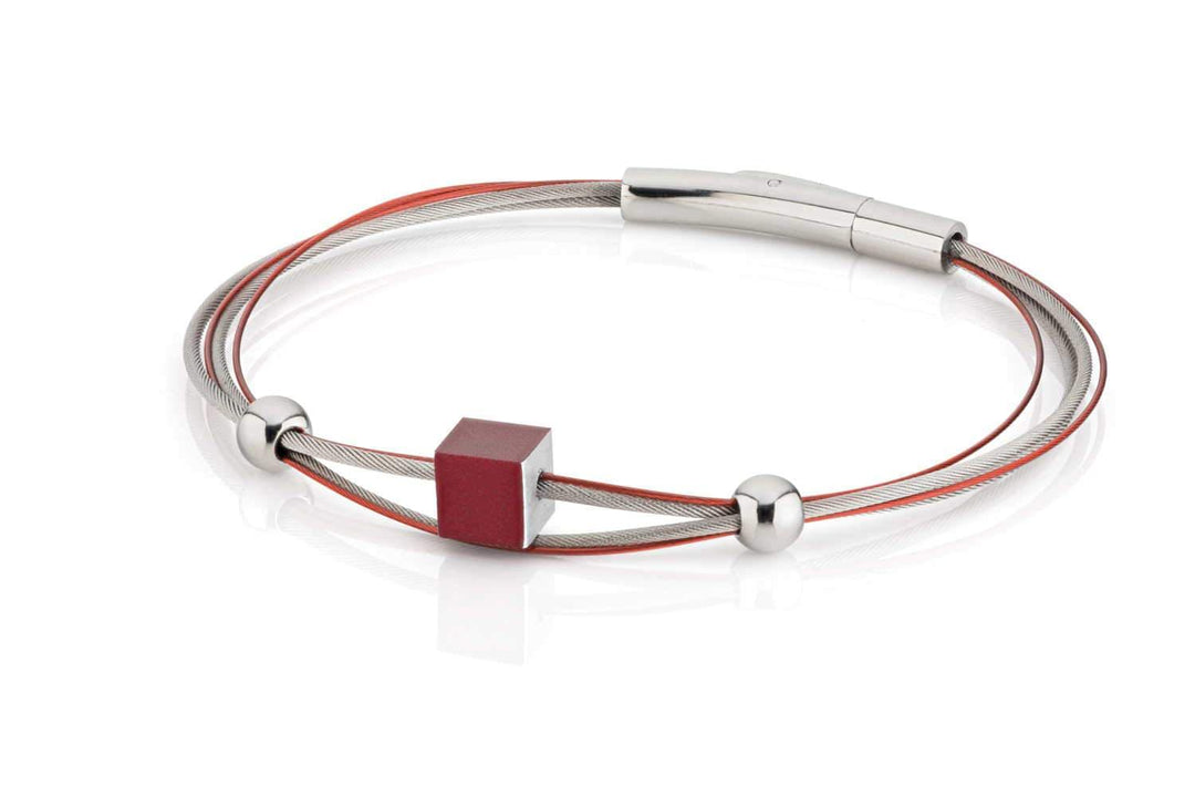 De Armband kubusje Rood A230R van CLIC Creations toont twee strakke, metalen banden—zilver en rood—versierd met een rode kubus en twee zilveren kralen. De glanzende, metalen bajonetsluiting complementeert de hypoallergene zilveren band perfect.