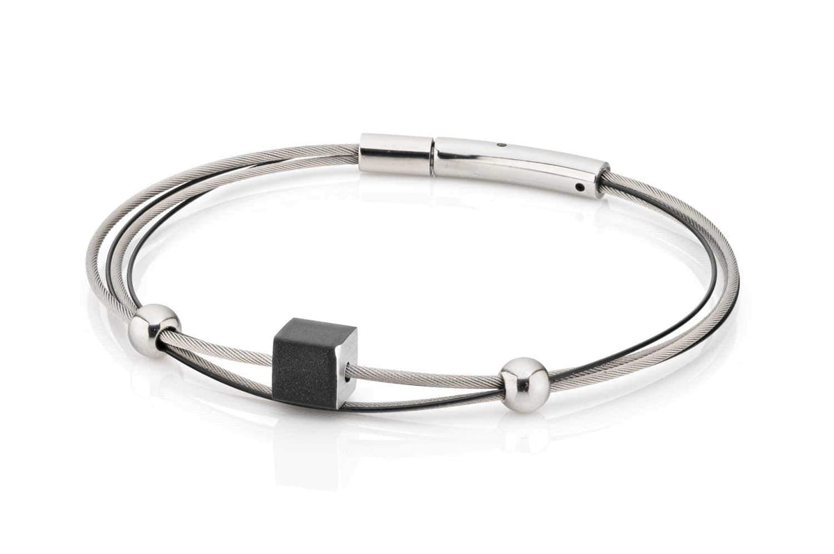 Armband mit schwarzem Würfel und silbernen Perlen auf einem flexiblen Draht.