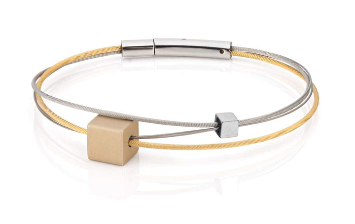 Clic Creations biedt de A231G: twee verweven armbanden, een gouden en een zilveren, met geometrische blokaccenten. Ze hebben een strak, minimalistisch ontwerp met een metalen sluiting en zijn elegant geplaatst tegen een witte achtergrond.