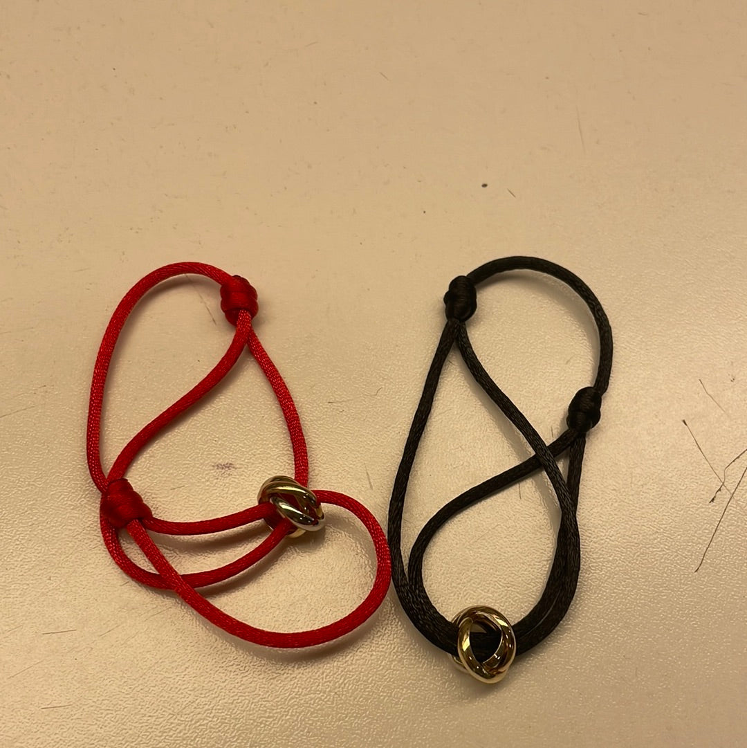 Zwei Armbänder mit roten und schwarzen Schnüren und goldenen Elementen