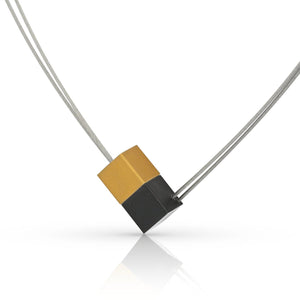 Collier mit zwei kubischen Anhängern in Schwarz und Gold, auf einem silbernen Draht.