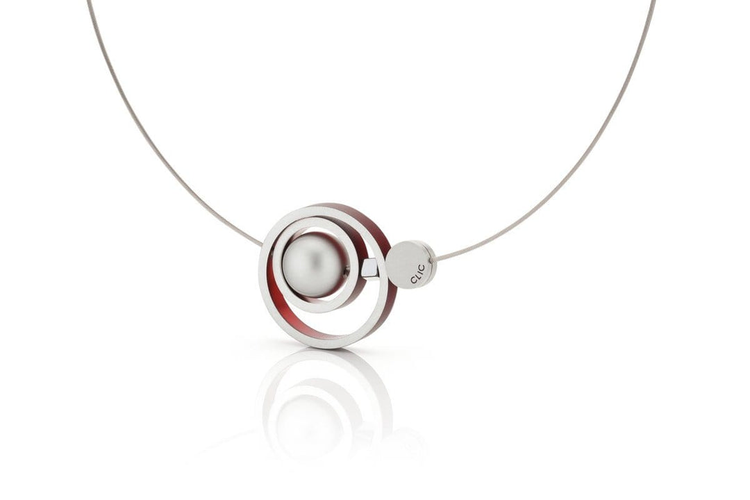 Ontdek de Collier Ringen in elkaar Rood C187R van CLIC Creations, een modern handgemaakt Nederlands sieraad met concentrische cirkels met een zilveren bol en een rode lus aan een strakke metalen ketting met een magneetsluiting.