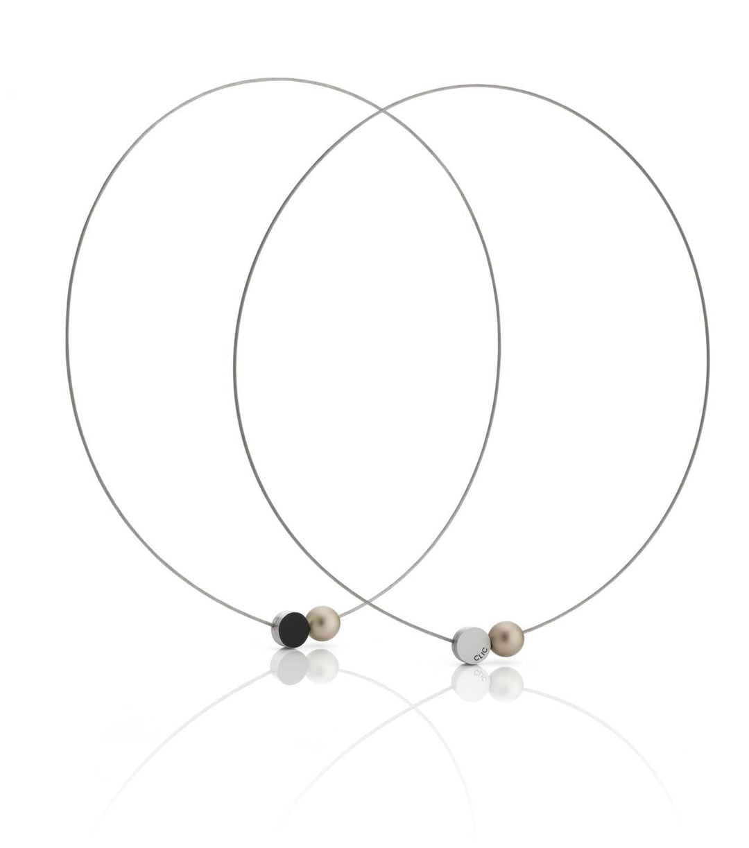 De Collier Mini Kogeltje Goud C192G van CLIC Creations bestaat uit twee dunne kettingen met kleine bolvormige kralen in zwart, beige en zilver en een magnetische sluiting. Ze zijn handgemaakt in Nederland en overlappen elegant met kralen die aan de voorkant op een reflecterend oppervlak zijn geplaatst.