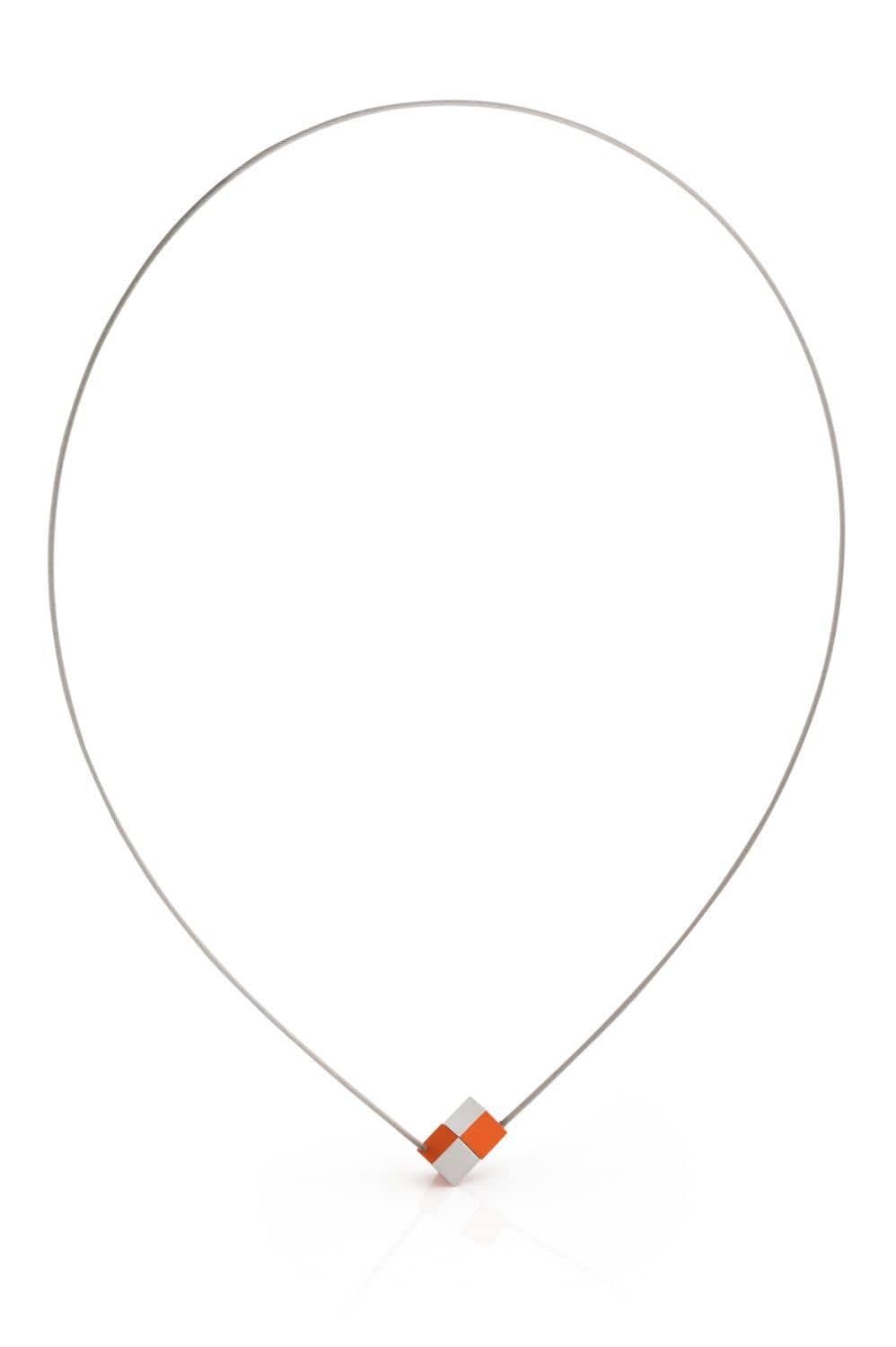 De Collier Twee kubusjes Oranje C205O van CLIC Creations is een minimalistische ketting met een dunne draadketting en een geometrische hanger. Met in elkaar grijpende oranje en zilveren blokken met een magnetische sluiting, biedt het een eenvoudig maar eigentijds ontwerp.