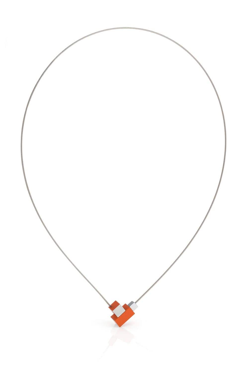 Het Collier Vierkantje en rechthoekje Oranje C206O van CLIC Creations is een minimalistische ketting met een dunne, zilverkleurige edelstalen collierdraad met een moderne oranje en grijze geometrische hanger. Het heeft een uniek ontwerp van in elkaar grijpende rechthoekige vormen en een magnetische sluiting.
