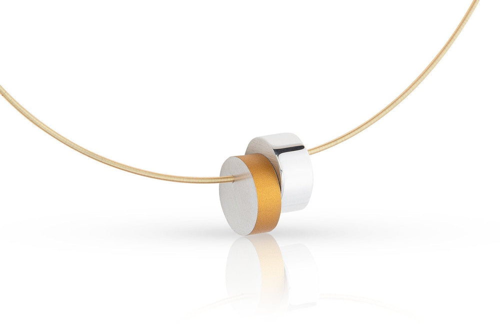 De CLIC Creations Collier Cilinders tegen elkaar Goud|Geel C250G is een minimalistische ketting met een dunne gouden ketting met een moderne ronde hanger van gestapelde zilveren en gouden schijven. Dit unieke ontwerp is handgemaakt in Nederland en biedt een strakke stijl die subtiel licht reflecteert.