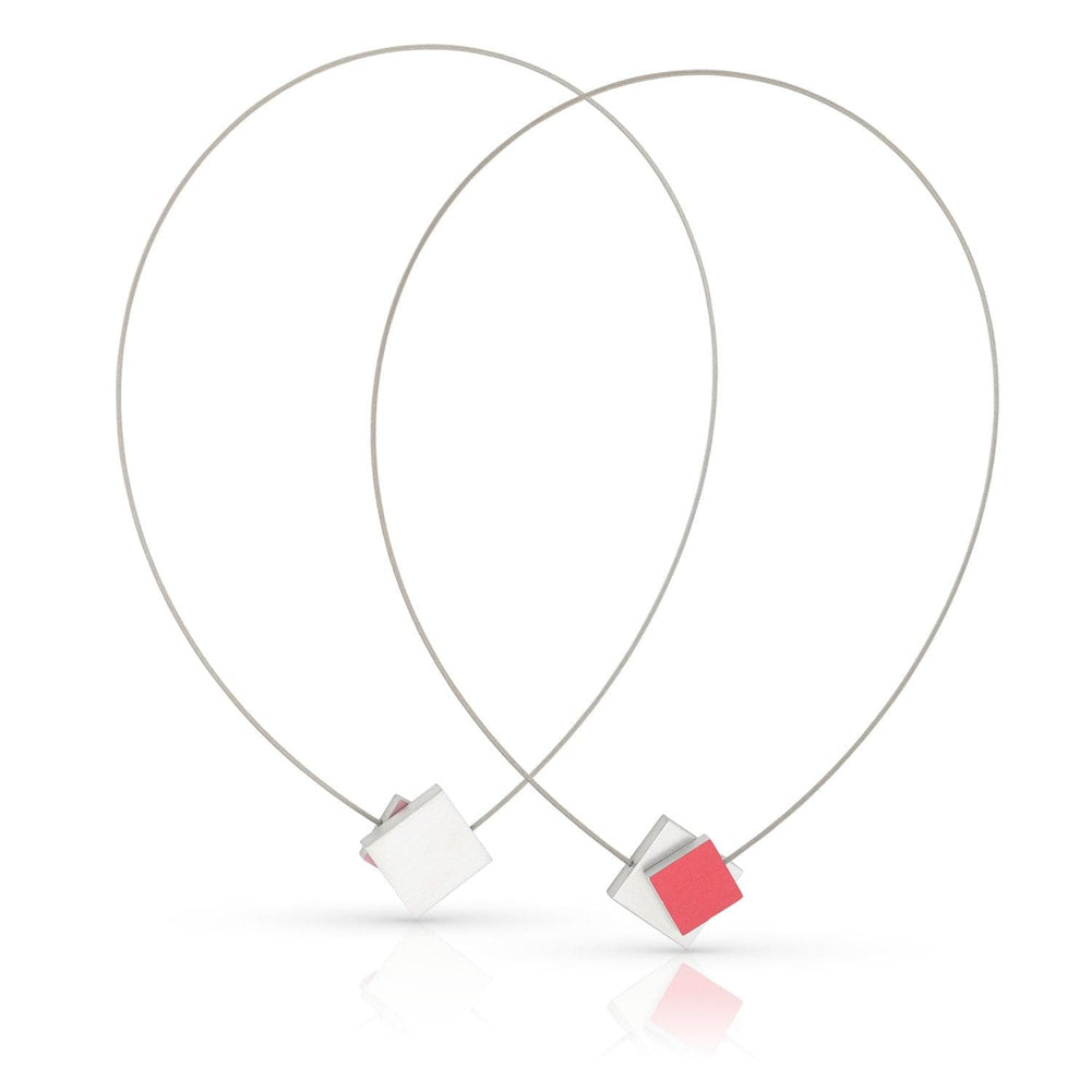 CLIC Creations Collier Vierkant met gekleurd vierkant C263R bevat twee minimalistische kettingen met draadlussen en centrale kubussen, een rode en een witte. De elegante druppelvormen versterken het geometrische ontwerp, terwijl de magnetische sluiting zorgt voor gemakkelijk dragen. Perfect voor elk stijlvol ensemble.