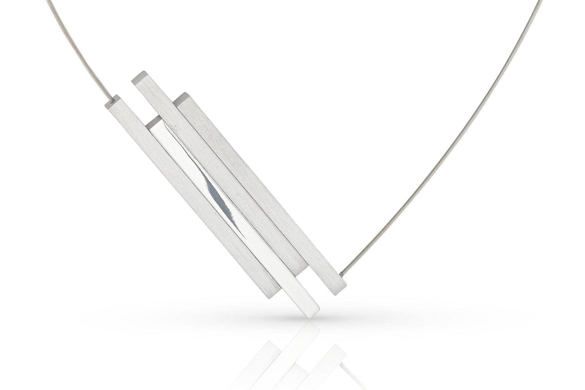 De C264-ketting van Clic Creations heeft een minimalistisch ontwerp met drie dunne, rechthoekige zilveren staafjes die aan een fijne ketting zijn bevestigd. Hierdoor ontstaat een geometrische en eigentijdse look tegen een witte achtergrond.