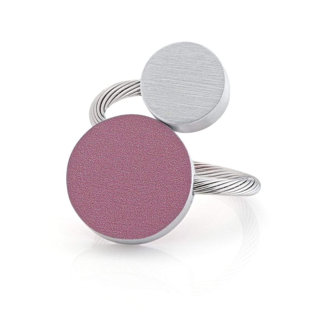 De CLIC Creations Ring Twee ronde vormen Roze R5RO toont een uniek ontwerp met twee cirkelvormige elementen: een grotere roze textuur en een kleinere zilveren, verbonden door een strakke, gedraaide zilveren band. Handgemaakt in Nederland.