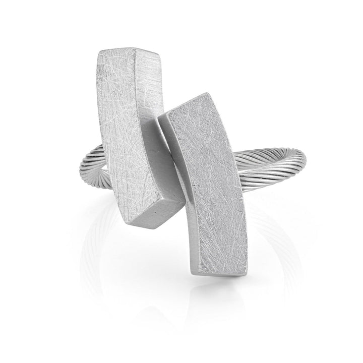 Deze moderne zilveren ring van CLIC Creations, handgemaakt in Nederland, heeft een uniek ontwerp met twee langwerpige, getextureerde rechthoeken die diagonaal overlappen op een gedraaide band. De Ring twee boogjes naar binnen past op de meeste R8 toont minimalistische stijl met gepolijst en mat contrast.