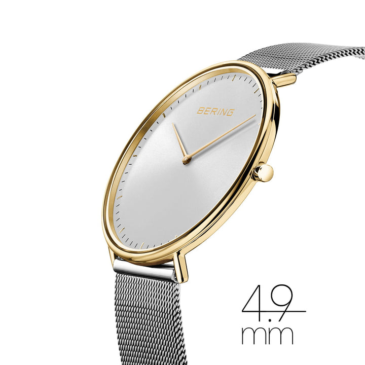 De Bering 15739-010 is een strak dameshorloge met een goudkleurige roestvrijstalen kast en zilveren meshband, met gouden uur- en minutenwijzers op een minimalistische witte wijzerplaat met de merknaam. De tijdloze elegantie wordt belichaamd in de opmerkelijke dikte van 4,9 mm.