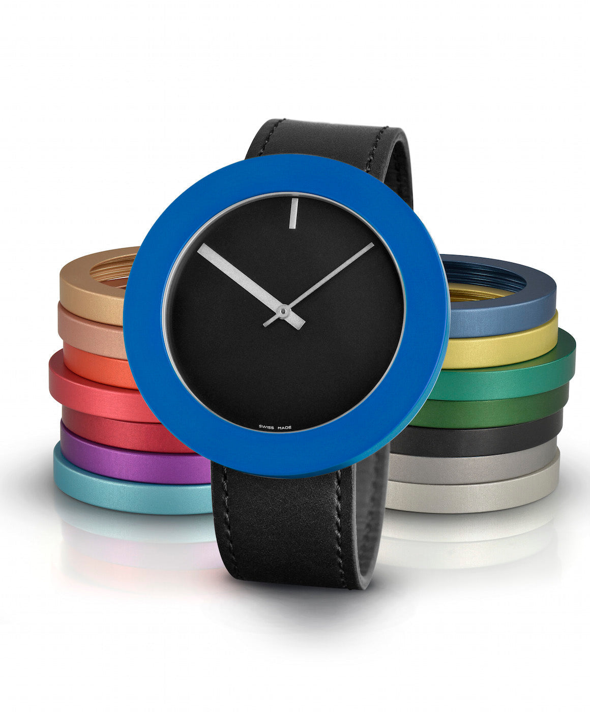 Uhr mit schwarzem Zifferblatt, blauer Lünette und schwarzem Lederarmband, im Hintergrund bunte Ringe