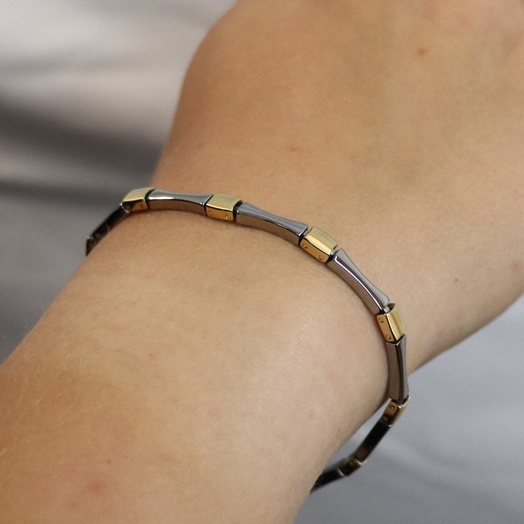 Een close-up van een pols versierd met de Boccia Titanium Armband Bicolor 03037-04, met afwisselend zilveren en gouden schakels van Boccia tegen een zachte, neutrale achtergrond.