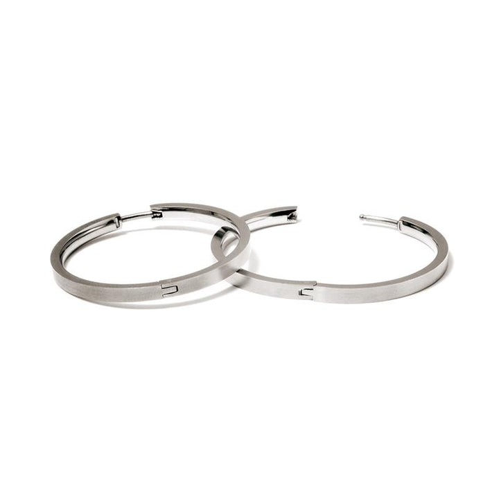 Een paar Boccia Titanium Oorringen 0516-01 van Boccia, met een minimalistisch zilverkleurig ontwerp en gladde afwerking in duurzaam materiaal, worden overlappend getoond op een witte achtergrond.