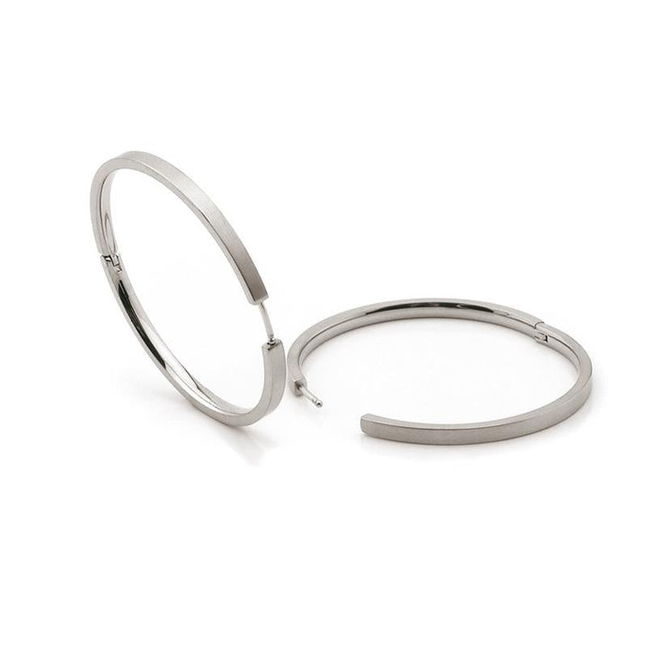 Op een witte achtergrond worden twee Boccia Titanium Oorringen 0508-01 zilveren creolen afgebeeld; één rechtopstaand en de andere plat, wat het strakke design en de gladde afwerking benadrukt.