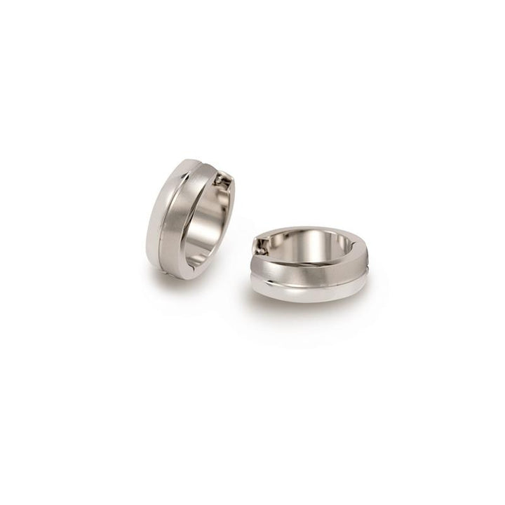 Twee zilverkleurige oorbellen worden op een witte achtergrond weergegeven; Boccia's Titanium Oorringen 0539-05 zijn eenvoudig, gepolijst met een glad cirkelvormig ontwerp. Eén staat rechtop, terwijl de andere zachtjes op zijn kant rust.