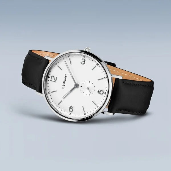 De Bering 14040-404 is een minimalistisch herenhorloge met een witte wijzerplaat, zwarte markers en wijzers, zwarte leren band, quartz uurwerk en het BERING-logo op de wijzerplaat. Weergegeven tegen een lichtverloop achtergrond voor een stijlvolle look.