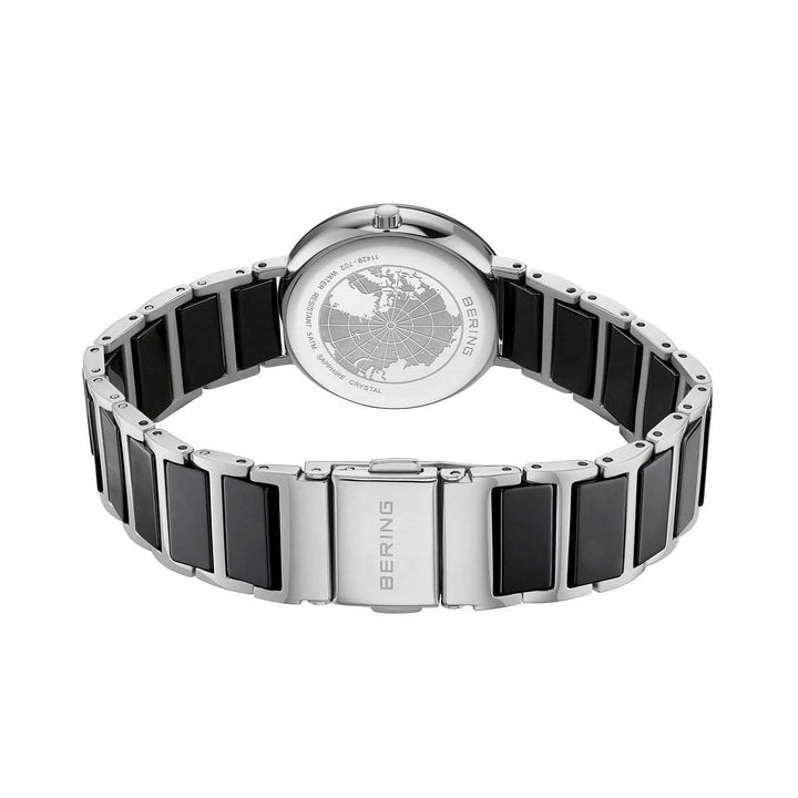 Het Bering dames horloge zwarte wijzerplaat - 11429-702 is een zilverkleurig dameshorloge met een zwarte keramische inlegband, een gegraveerde wereldkaart op de achterkant van de kast, duurzaam saffierglas en elegante details van Bering.
